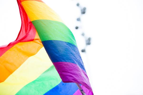 Rainbow flag blowing in the wind with a white blurred background  