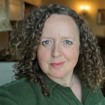 An image of Charlotte Smith looking directly at the camera, wearing a green top. 