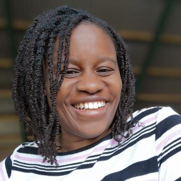 An image of Elisha Ward smiling at the camera, wearing a stripy top. 