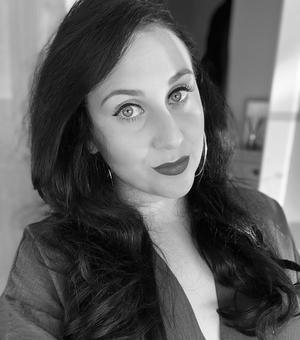 A black and white photo of Bryony. She has long dark hair and is wearing a dress. 